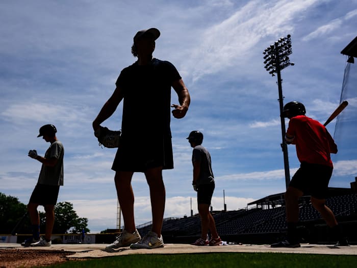 Minor league baseball players stand on a field.